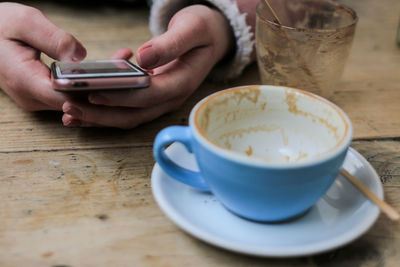 Close-up of hand holding coffee cup on table