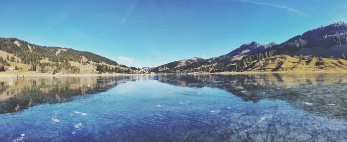 Scenic view of lake and mountains against blue sky