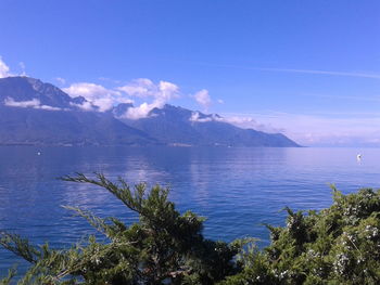 Scenic view of sea and mountains against blue sky