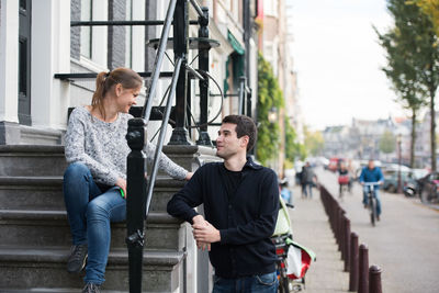 Woman talking with man while sitting on steps