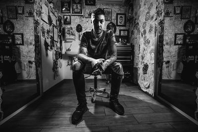 Full length portrait of young man sitting on seat