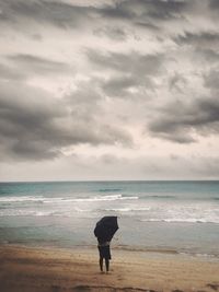 Silhouette woman standing on beach against sky