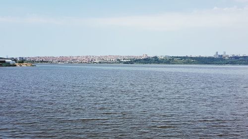 Scenic view of sea by townscape against sky