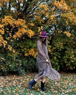 Woman with umbrella walking on autumn leaves