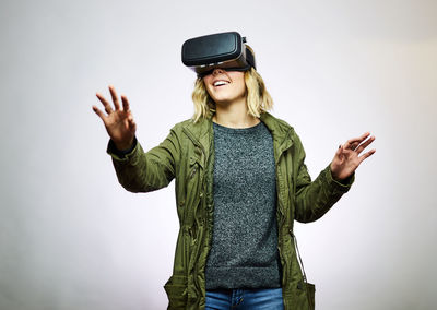 Smiling young woman using virtual reality against white background