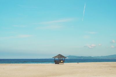 Lifeguard hut on beach against blue sky