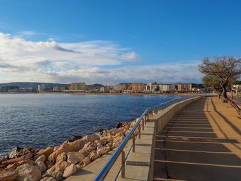 View of city at waterfront against cloudy sky