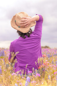 Rear view of woman sitting on field against sky