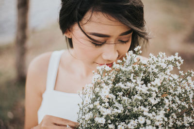 Close-up of woman smelling white flowers