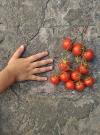 Cropped hand by tomatoes on footpath