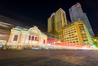 Light trails on road against buildings at night