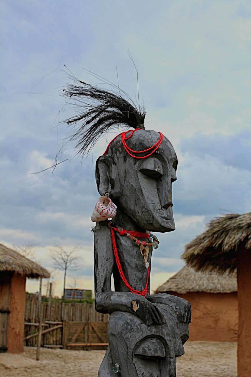 WOMAN STANDING AGAINST CLOUDY SKY