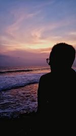 Silhouette man looking at sea against sky during sunset