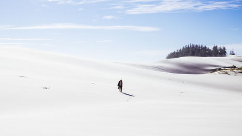 Full length of woman standing on snow against sky during sunny day