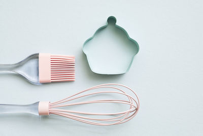 Pink silicone kitchen utensils on light blue background top view