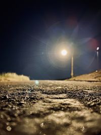 Surface level of road on field against bright sun