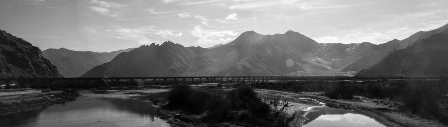 Scenic view of dam and mountains against sky