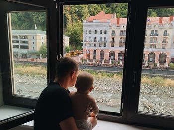 Rear view of woman looking through window