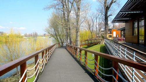 Footbridge by river against sky