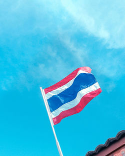 Low angle view of flag against blue sky