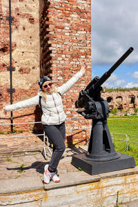 Full length of woman standing against brick wall