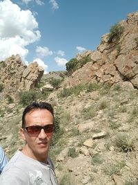 Man wearing sunglasses standing by mountain