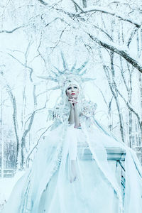 Portrait of woman standing on snow covered tree