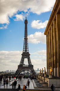 Tourists in front of eiffel tower against cloudy sky