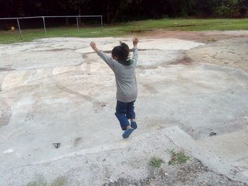 Rear view of playful girl jumping from retaining wall at park