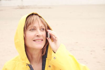 Close-up of senior woman talking on mobile phone while standing at beach 