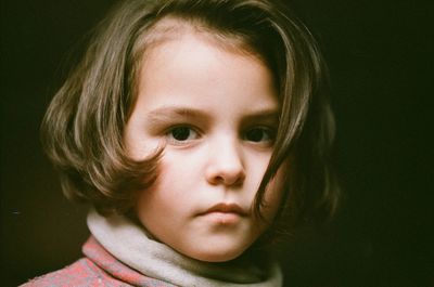 Close-up portrait of cute girl against black background