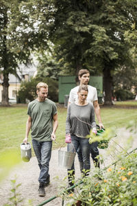 Friends with gardening equipment walking by garden