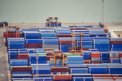 Stack of pier full of cargo container against blue sky