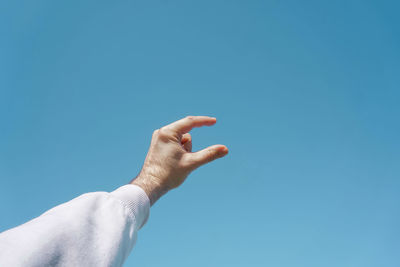 Cropped hand gesturing against blue background