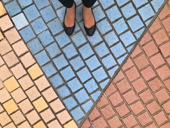 Low section of woman standing on cobbled footpath