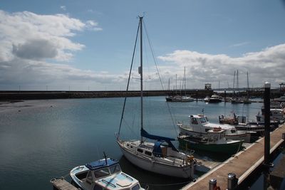 Boats moored at harbor against sky