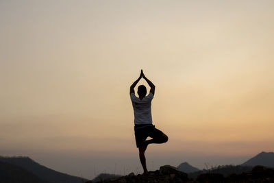 Full length of silhouette man with arms raised against sky during sunset