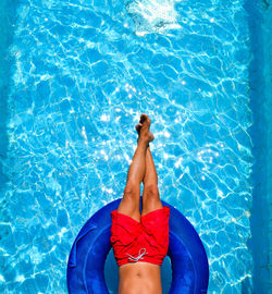 Low section of man relaxing in inflatable ring on swimming pool