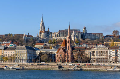 Buildings by sea against clear sky