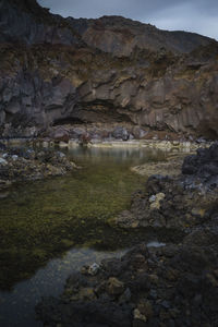 Rock formation by lake against sky