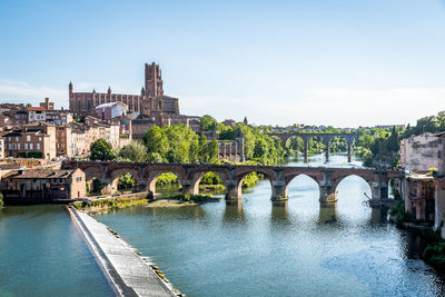 Arch bridge over river against buildings in city