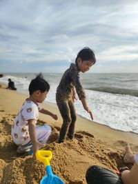 Side view of sibling playing at beach