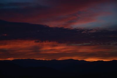 Scenic view of silhouette mountains against orange sky