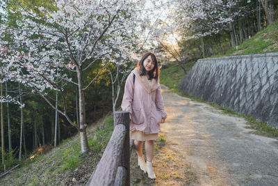 Portrait of woman smiling while standing against cherry blossoms