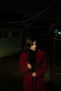 Full length of woman standing against illuminated tree at night