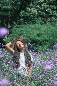 Portrait of smiling young woman standing by plants on field