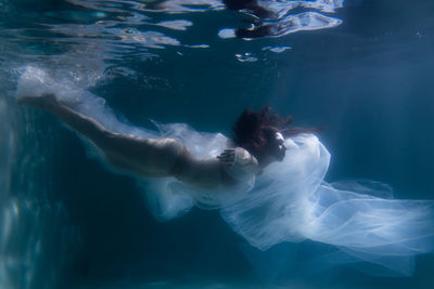 Woman with curtain swimming in pool