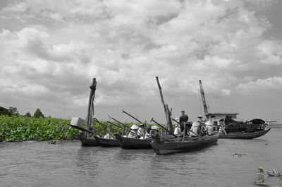 Boats in sea against cloudy sky