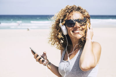 Smiling woman listening music at beach