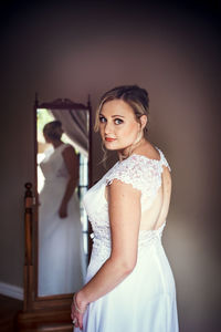Portrait of young woman standing against wall